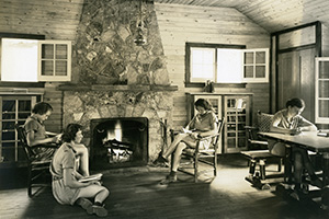 Vintage photo of four people sitting by the hearth in a camp lodge