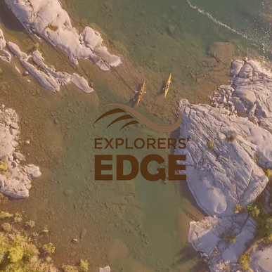 Aerial drone shot of kayaks along a coastline with logo for Explorers' Edge