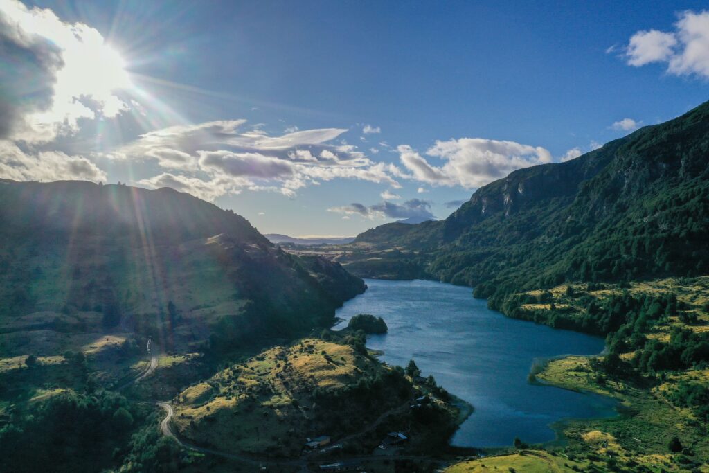 Mountain valley with a winding lake under scattered clouds