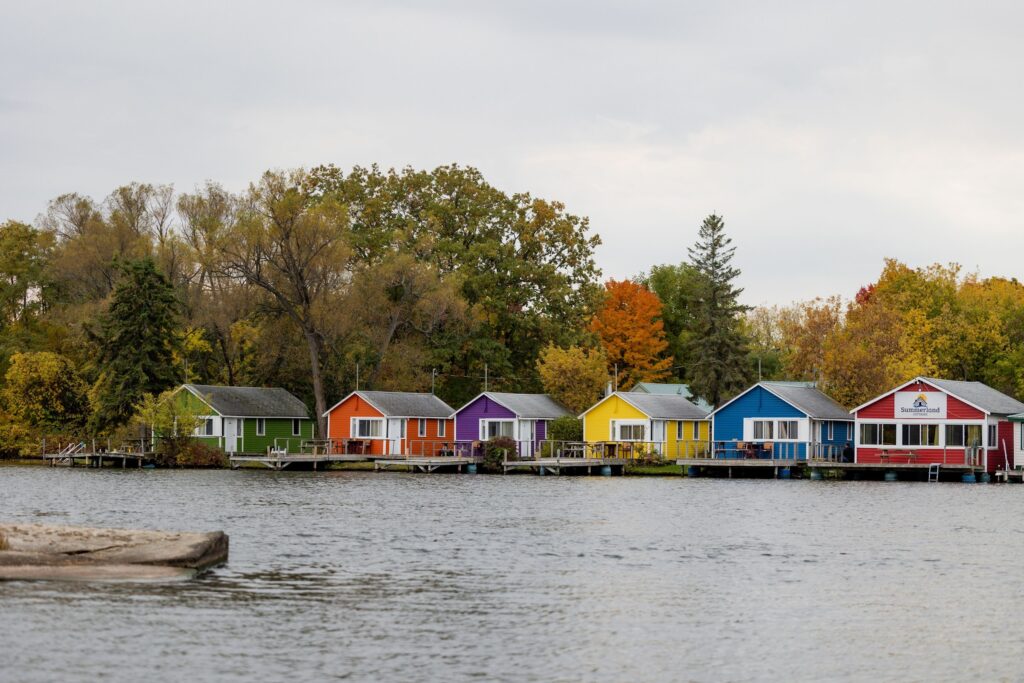 Colourful boathouses on a lake surrounded by fall trees