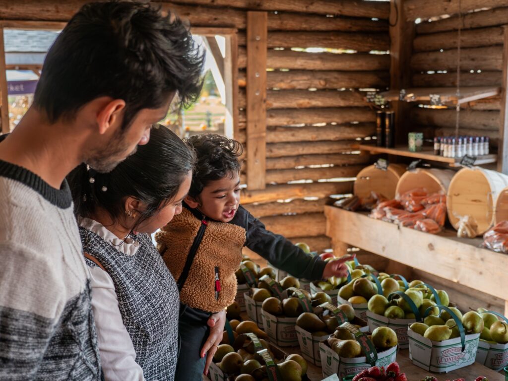 Family choosing produce at a farm market stand in fall