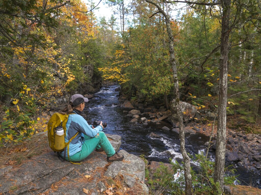 Hiker resting beside a forest creek in autumn