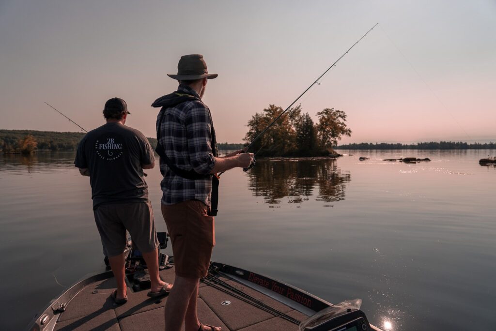 Two anglers fishing from a boat at dusk