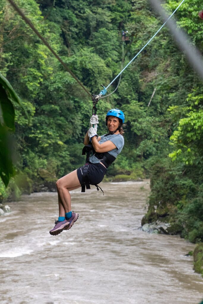 Smiling guest on a zipline above a forest gorge