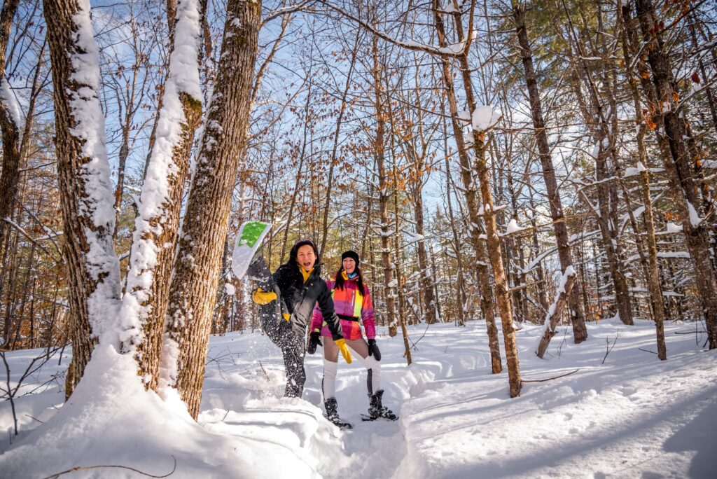 Two people walking through a snowy birch forest